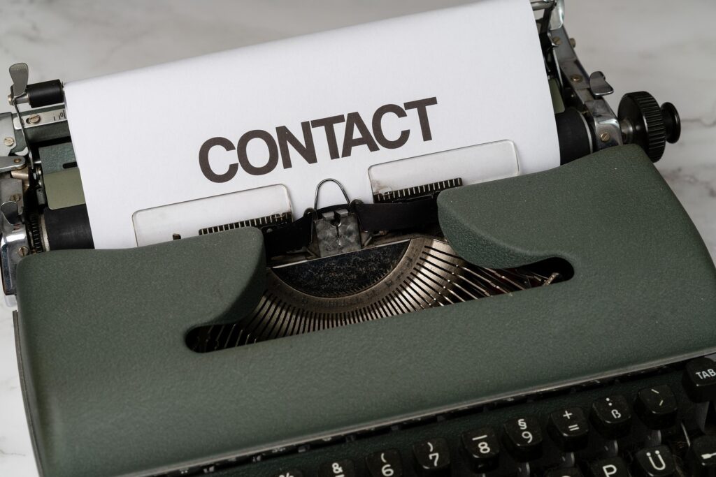 Schreibmaschine mit eingespanntem Blatt, auf dem "Contact" geschrieben steht.
