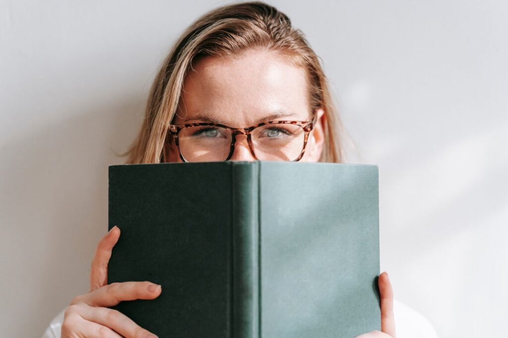 Frau, die ein Buch halb vor ihr Gesicht hält