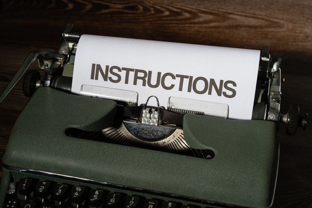Schreibmaschine mit eingespanntem Papier, auf dem "Instructions" geschrieben steht.